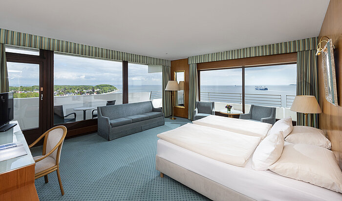 Spacious room with sea view, seating area and desk at Maritim Hotel Travemünde