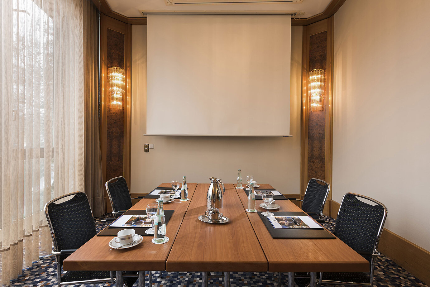 Compact meeting room with screen, daylight and conference table at Maritim Hotel Ulm.