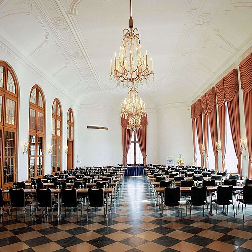 Elegant event hall at Maritim Hotel Fulda with chandeliers, high windows, and stylish seating for events.