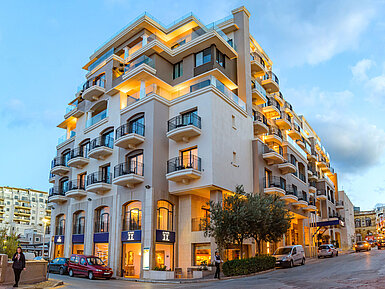 Elegant hotel exterior with balconies and warmly lit facade during evening twilight