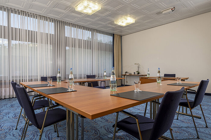 U-shaped meeting room with blue chairs, daylight and curtains at Maritim Hotel Travemünde