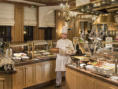 Breakfast buffet at the "Rôtisserie" restaurant in Maritim Hotel Bonn with a variety of dishes and a friendly chef.