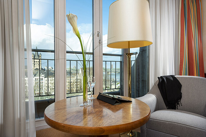 Classic room at Maritim Hotel Cologne with a view of the Rhine,featuring a cozy seating area and an elegantly decorated table