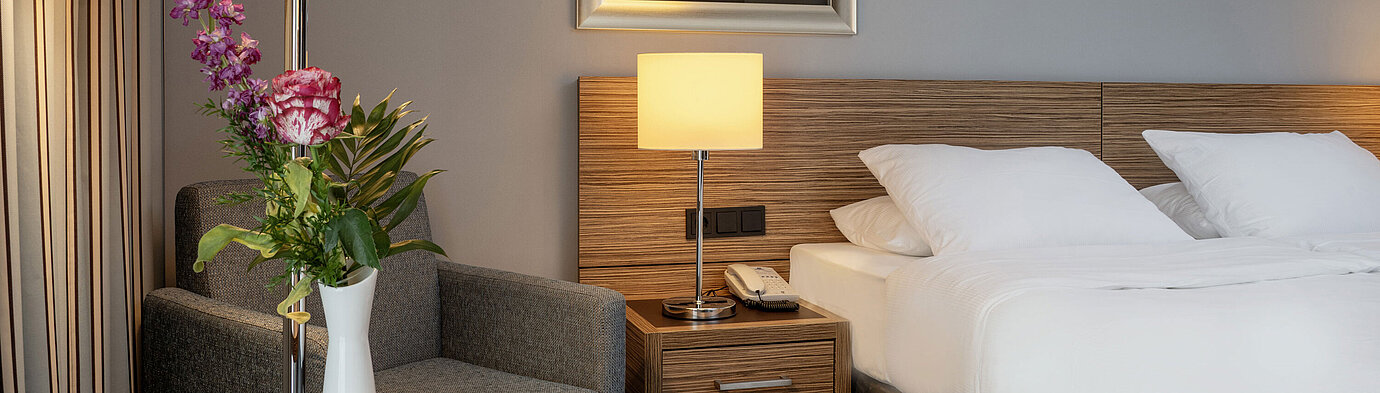 Cozy seating area with a flower vase next to the comfortable bed in the Superior Room at Maritim Hotel Darmstadt