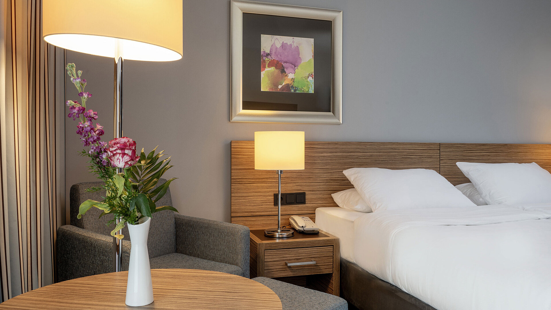 Cozy seating area with a flower vase next to the comfortable bed in the Superior Room at Maritim Hotel Darmstadt