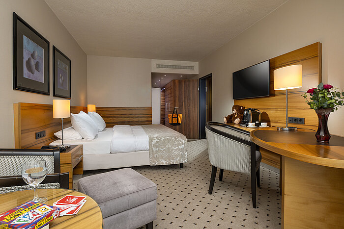 Comfort room at Maritim Hotel Bad Homburg with double bed, playing cards, teddy bear, and stylish wood decor.