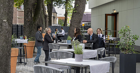 Modern terrace at Maritim Hotel Darmstadt with guests relaxing, trees in the background, and stylish gray furniture.