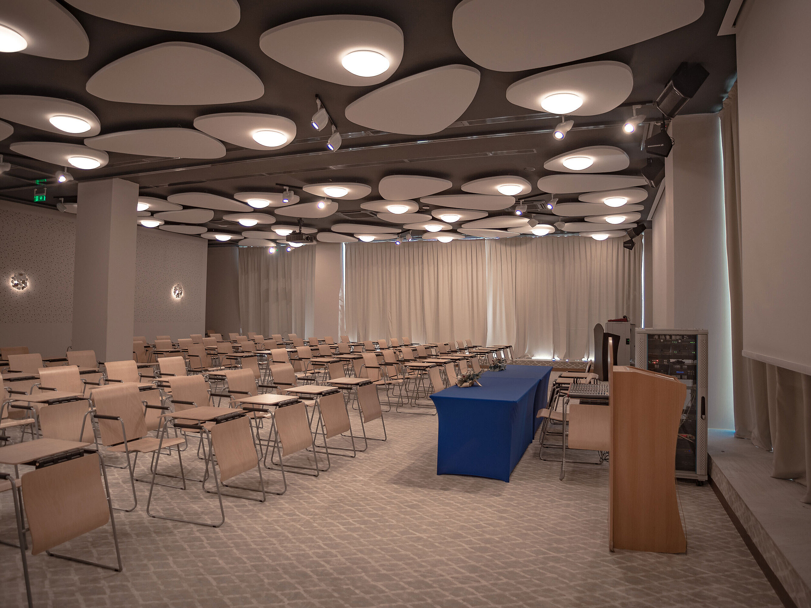 Large conference room with lectern, row seating and modern ceiling lighting