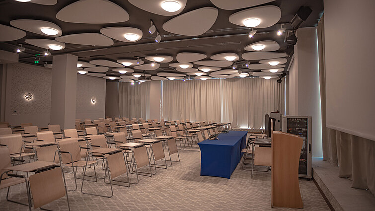 Large conference room with lectern, row seating and modern ceiling lighting