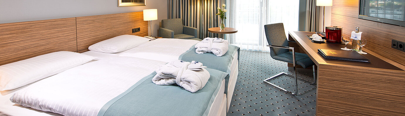Superior room at Maritim Hotel Darmstadt featuring stylish design, desk, cozy seating area, and double bed with bathrobes.