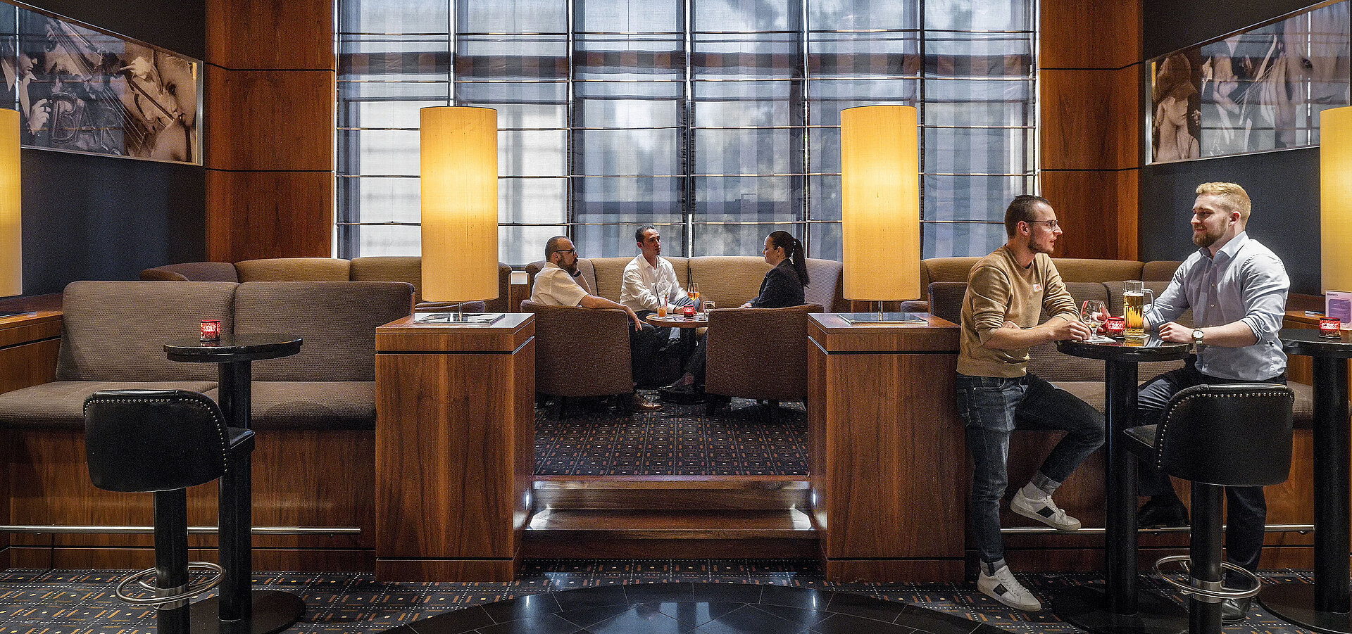 Cozy seating areas in the hotel bar at Maritim Hotel Düsseldorf with modern lighting and guests chatting.
