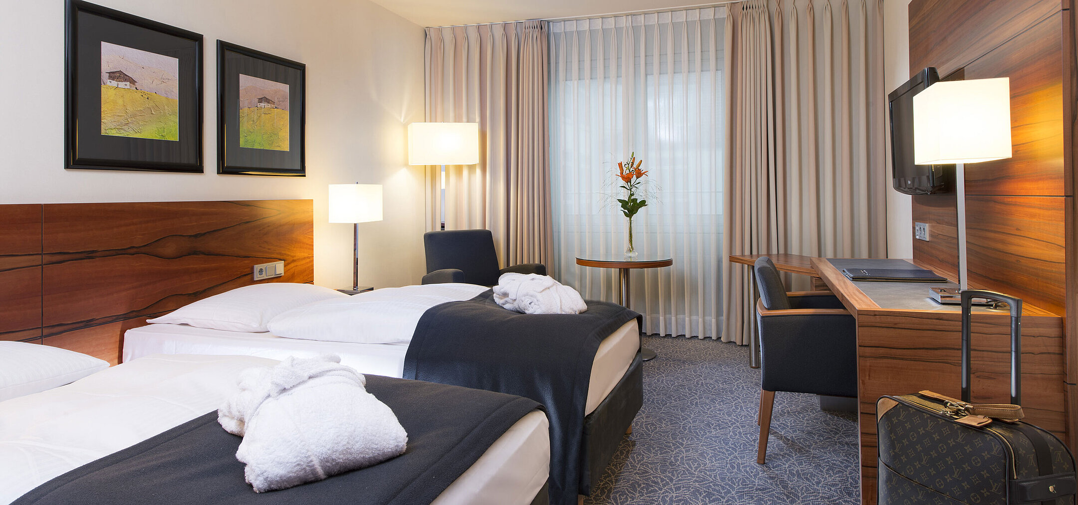 Comfortable twin room at the Maritim Hotel Munich. With separate beds, desk, TV, and seating area by the window.