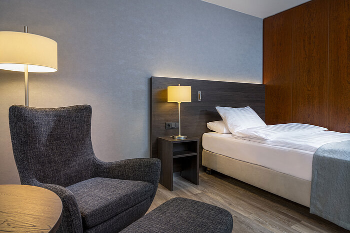 Modern Superior room at Maritim Hotel Bremen with cozy chair, bedside table, and ambient lighting.