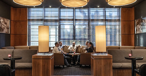 Cozy seating areas in the hotel bar at Maritim Hotel Düsseldorf with modern lighting and guests chatting.