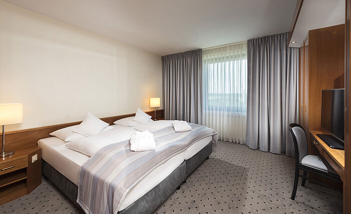 Junior Suite with cozy double bed, TV, desk, and large windows at Maritim Hotel Hannover.