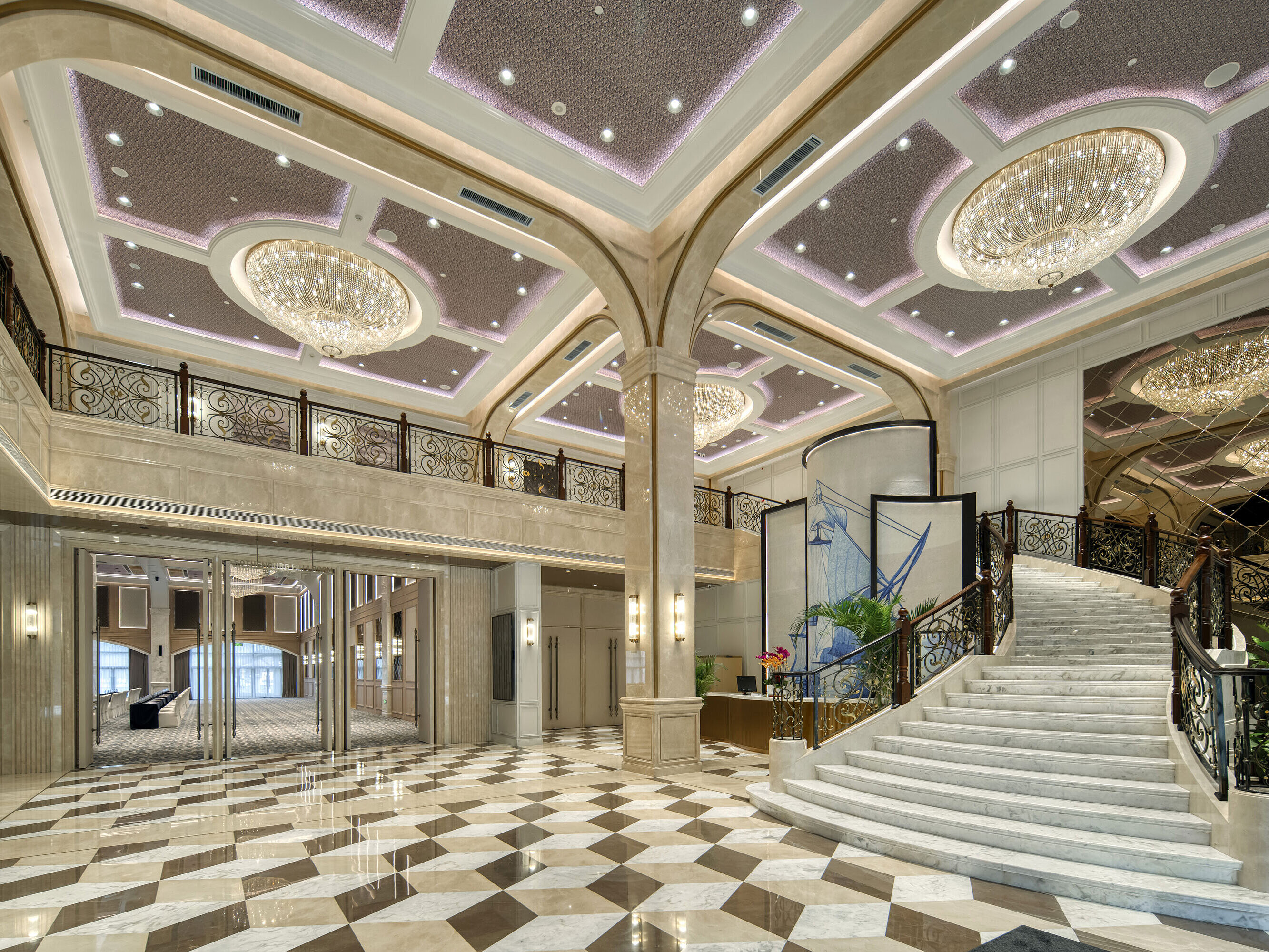 Spacious hotel lobby with marble flooring, opulent chandeliers and curved staircase at Maritim Hotel Taicang