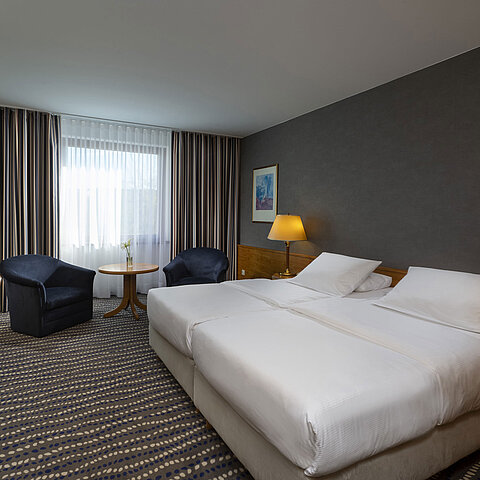 Hotel room with double bed, TV, desk, and cozy seating area, ideal for relaxation and comfort