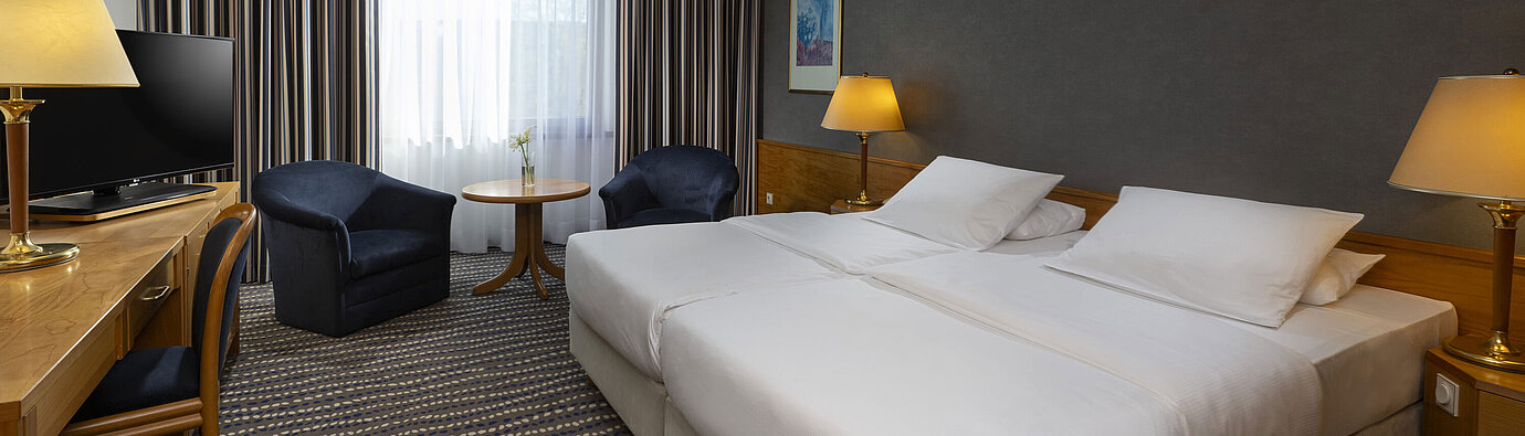 Hotel room with double bed, TV, desk, and cozy seating area, ideal for relaxation and comfort