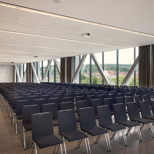 Large hall at Maritim Hotel Würzburg with rows of chairs, daylight and view of the city