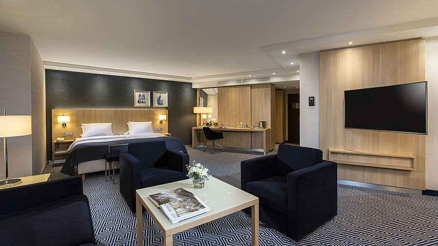 Spacious Junior Suite at Maritim Hotel Würzburg with a double bed and cozy seating area