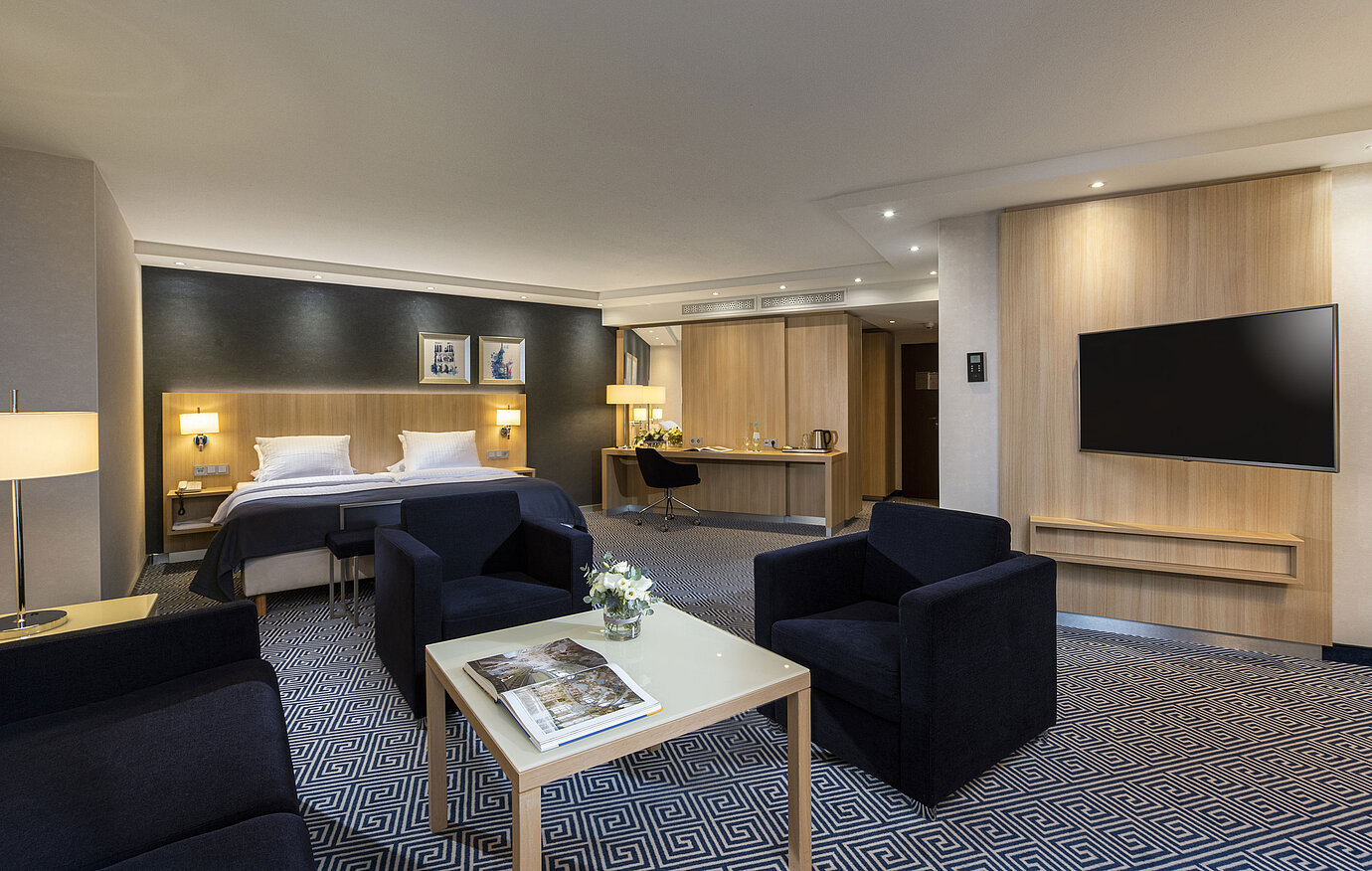 Spacious Junior Suite at Maritim Hotel Würzburg with a double bed and cozy seating area