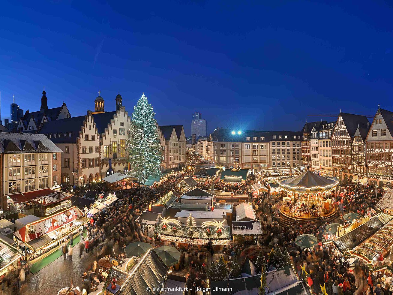 Christmas market on Römerberg square in Frankfurt with illuminated tree and historic half-timbered houses