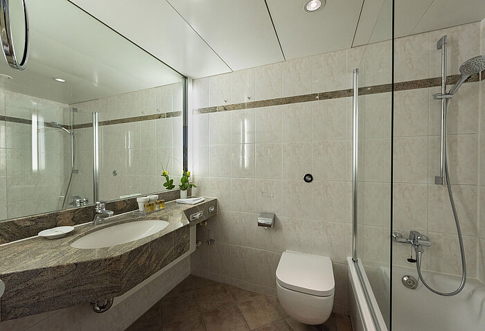 Bright bathroom at Maritim Hotel Travemünde with granite vanity, mirror and shower