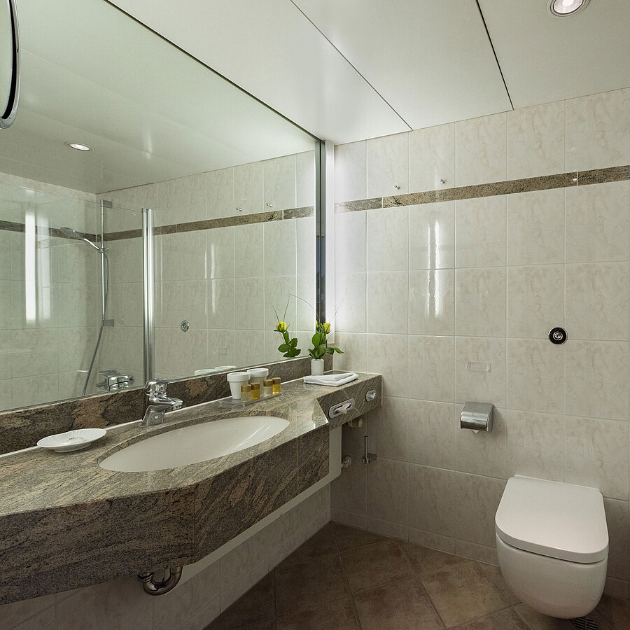 Bright bathroom at Maritim Hotel Travemünde with granite vanity, mirror and shower