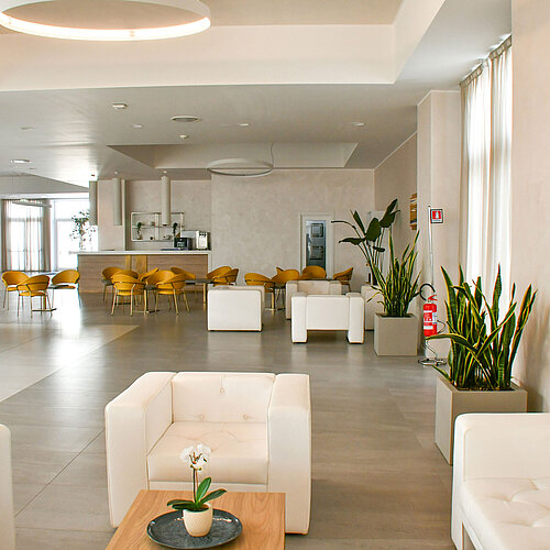 Bright lobby of Maritim Resort Calabria with white armchairs and yellow chairs
