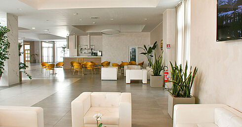 Bright lobby of Maritim Resort Calabria with white armchairs and yellow chairs