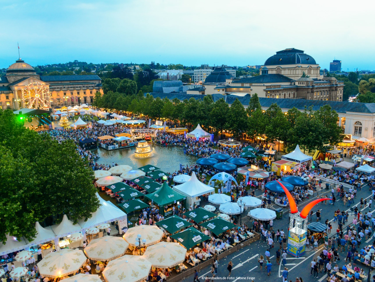 Aerial view of a lively city festival with stalls and water basin in Wiesbaden
