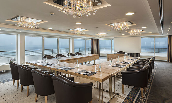 Salon Hamburg at Maritim Seehotel Timmendorfer Strand, conference room with sea view, L-shaped table, and elegant lighting.