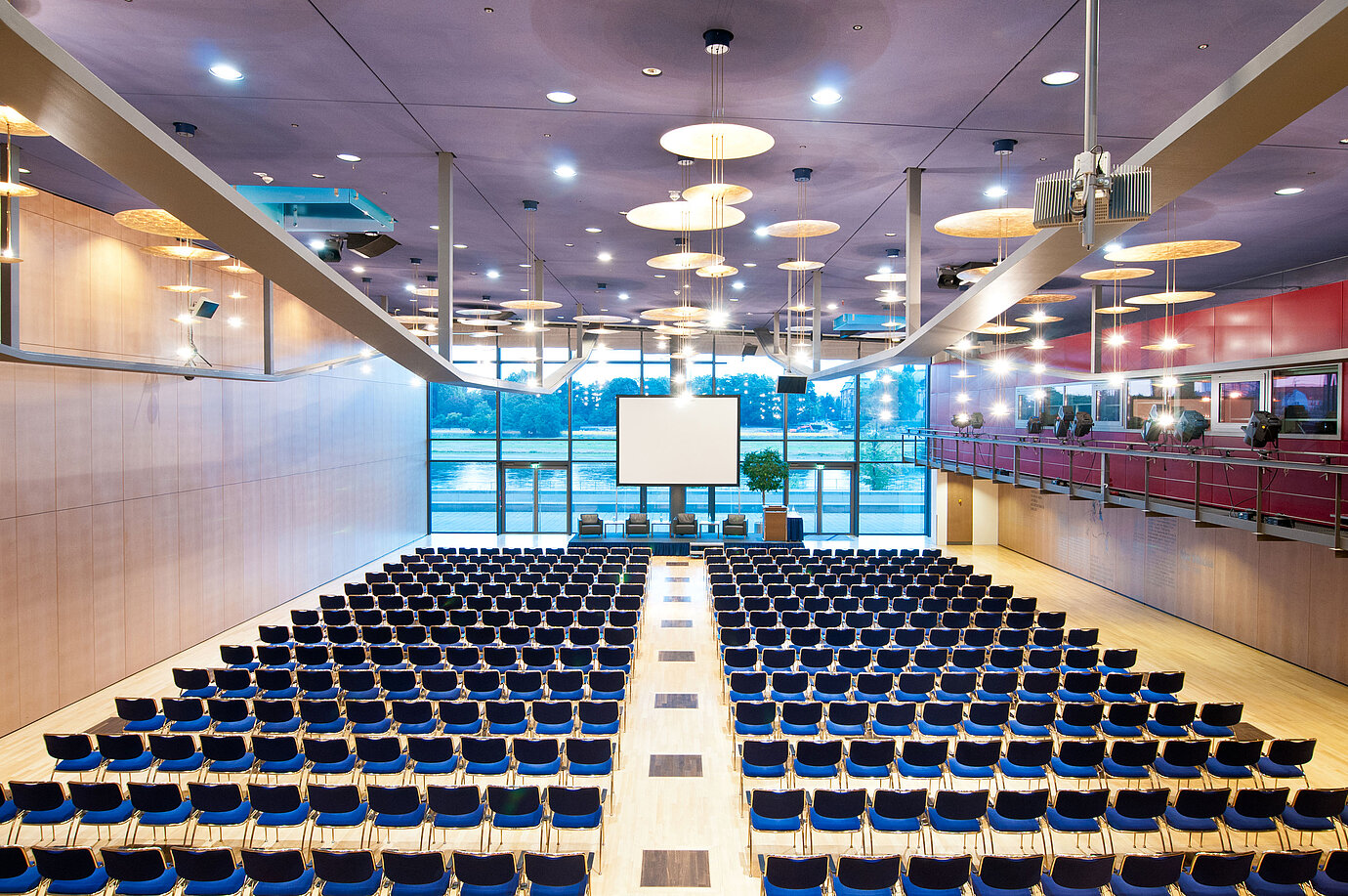 Large conference hall in Maritim Hotel Dresden with rows of blue chairs and a view of the Elbe River.