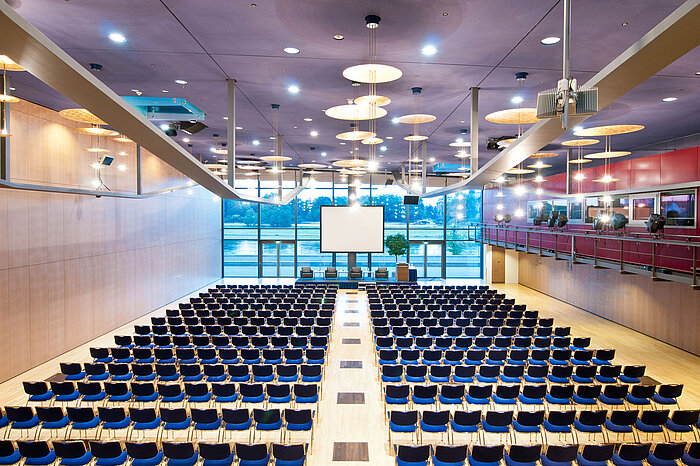 Large conference hall in Maritim Hotel Dresden with rows of blue chairs and a view of the Elbe River.