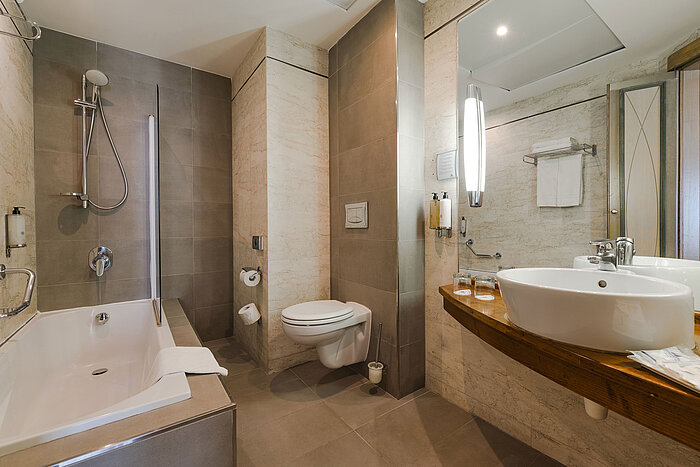Elegant hotel bathroom with bathtub, shower, washbasin and premium fittings
