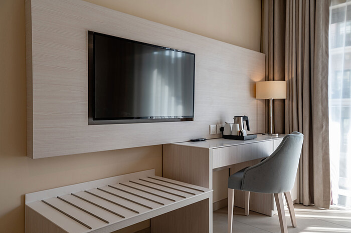 Work and entertainment area in the Junior Suite at Maritim Antonine Hotel & Spa Malta with desk, flat-screen television and tea and coffee station.