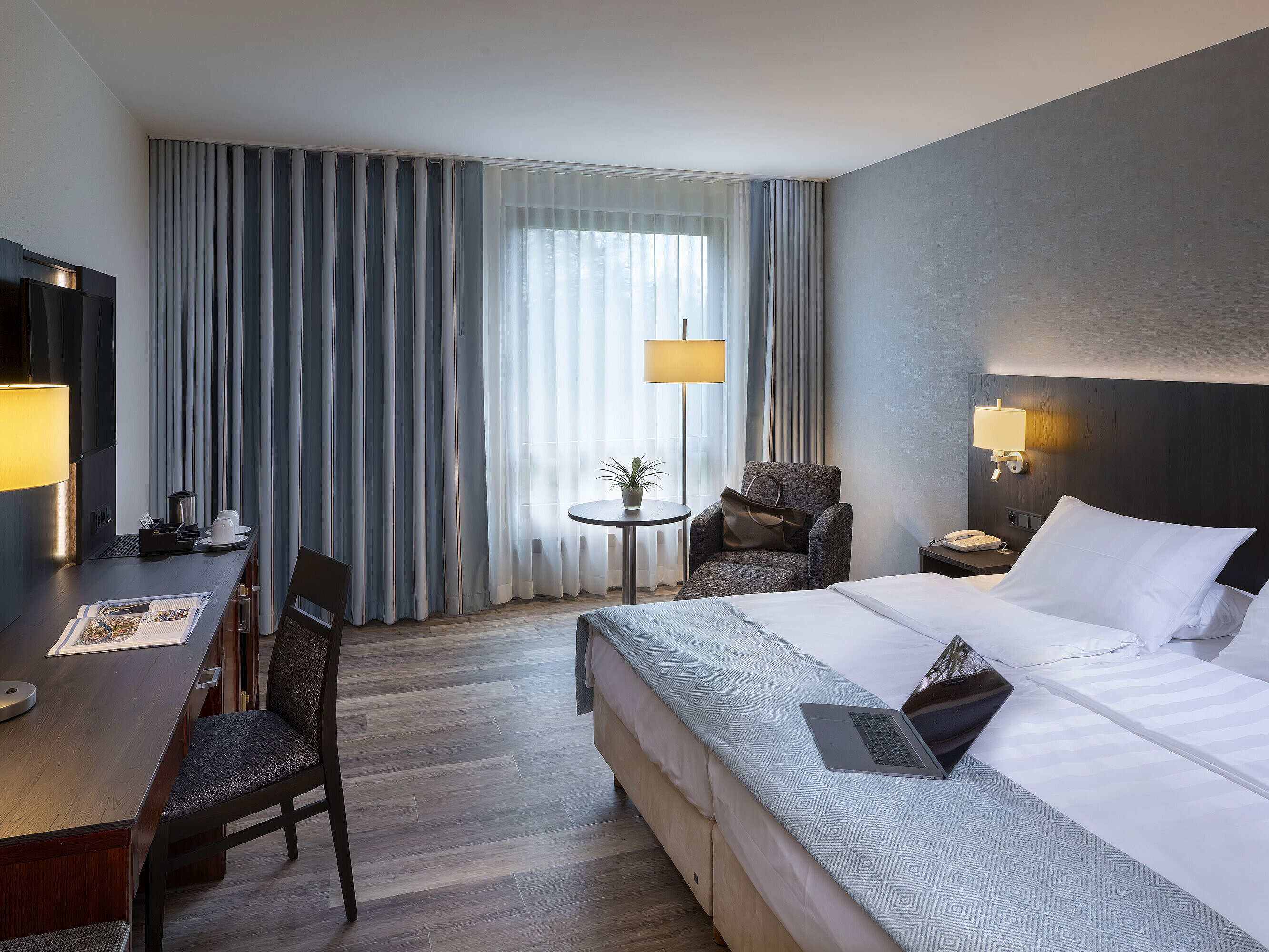 Bright single room at Maritim Hotel Bremen with stylish desk, cozy seating area, and large double bed.