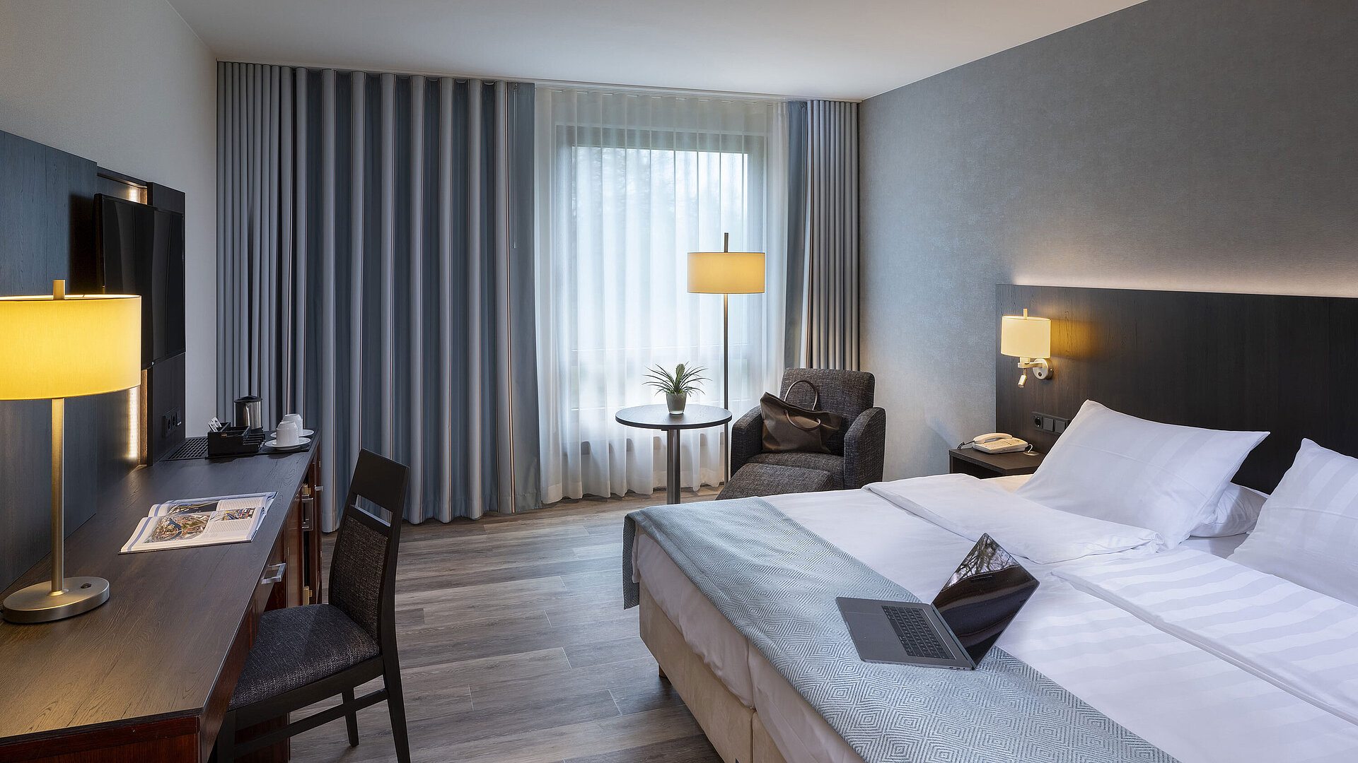 Bright single room at Maritim Hotel Bremen with stylish desk, cozy seating area, and large double bed.