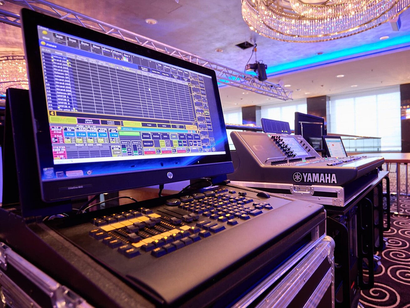 Professional lighting and mixing console in a modern event space with stage setup.