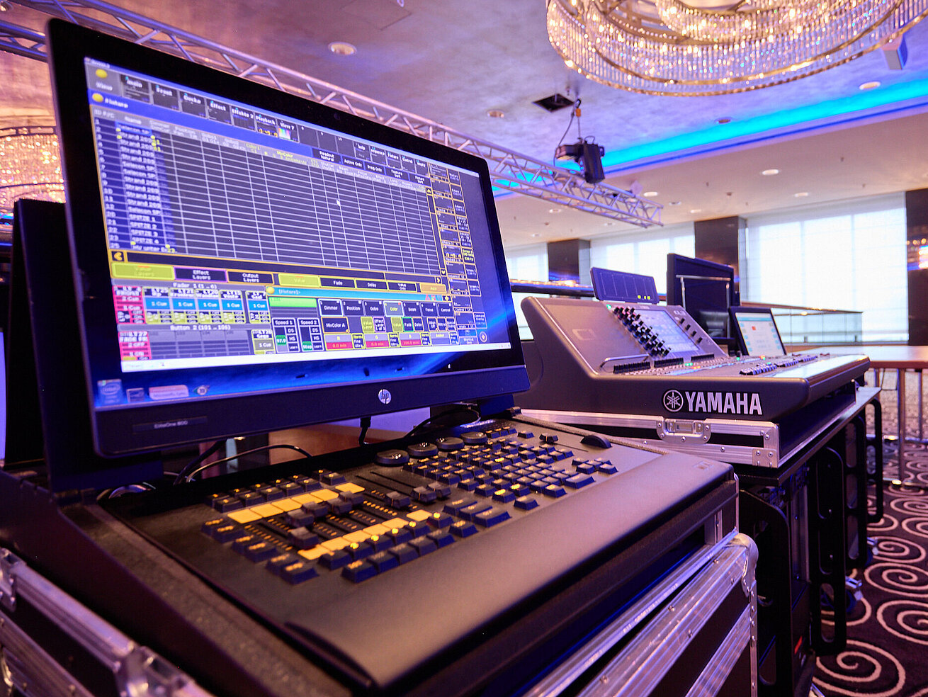 Professional lighting and mixing console in a modern event space with stage setup.