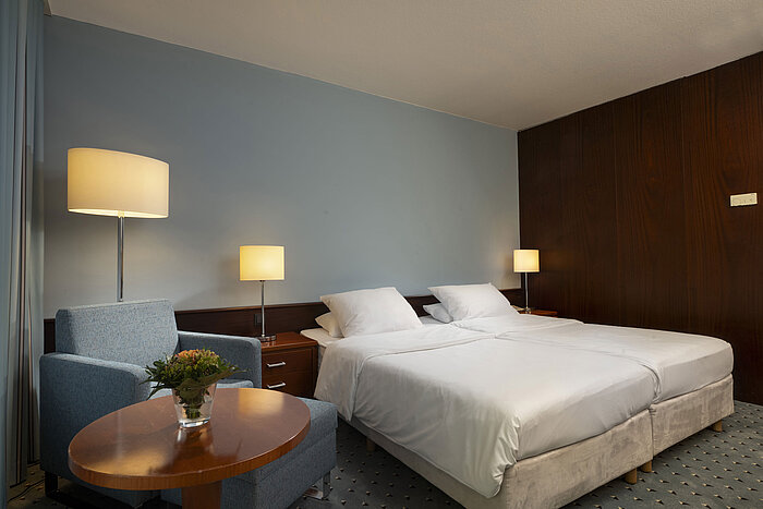 Cozy Classic room at Maritim Hotel Darmstadt with a double bed, an armchair, and soft lighting for an inviting atmosphere.