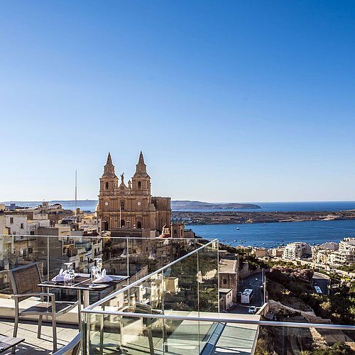 Panoramic rooftop view of church, coastline, town and blue Mediterranean Sea