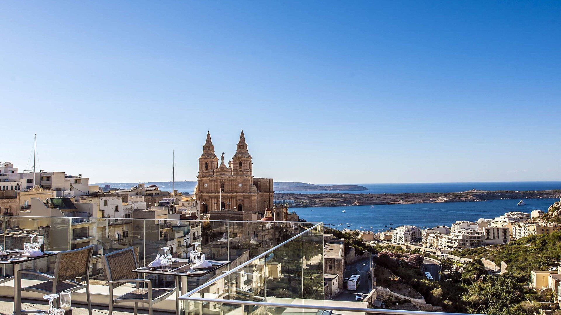 Panoramic rooftop view of church, coastline, town and blue Mediterranean Sea