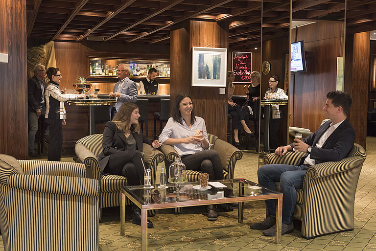 Guests enjoying drinks at the cosy bar of Maritim Hotel Bad Salzuflen with elegant wood panelling