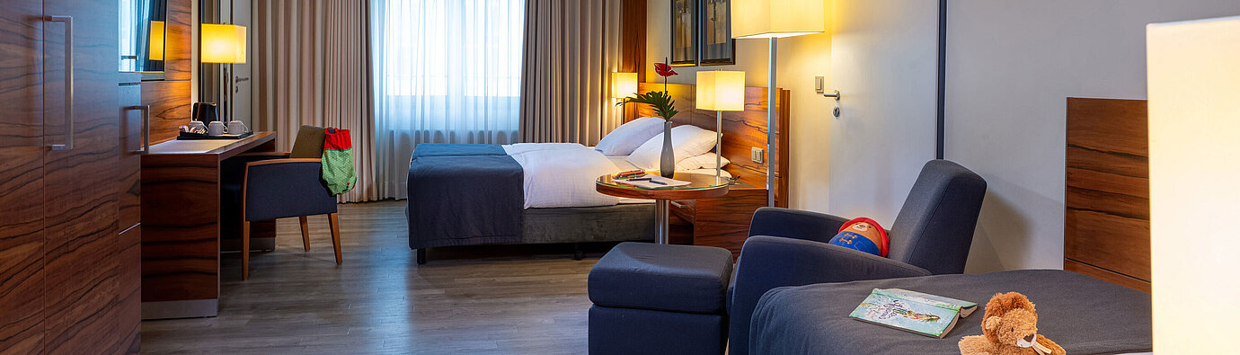 Spacious Comfort family room with two beds and desk at the Maritim Hotel München.