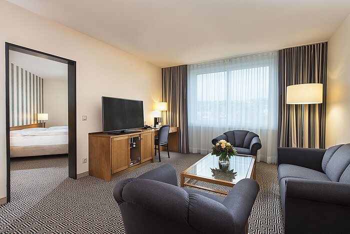 Spacious living area with sofa, armchair, TV and desk in the suite at the Maritim Hotel Stuttgart