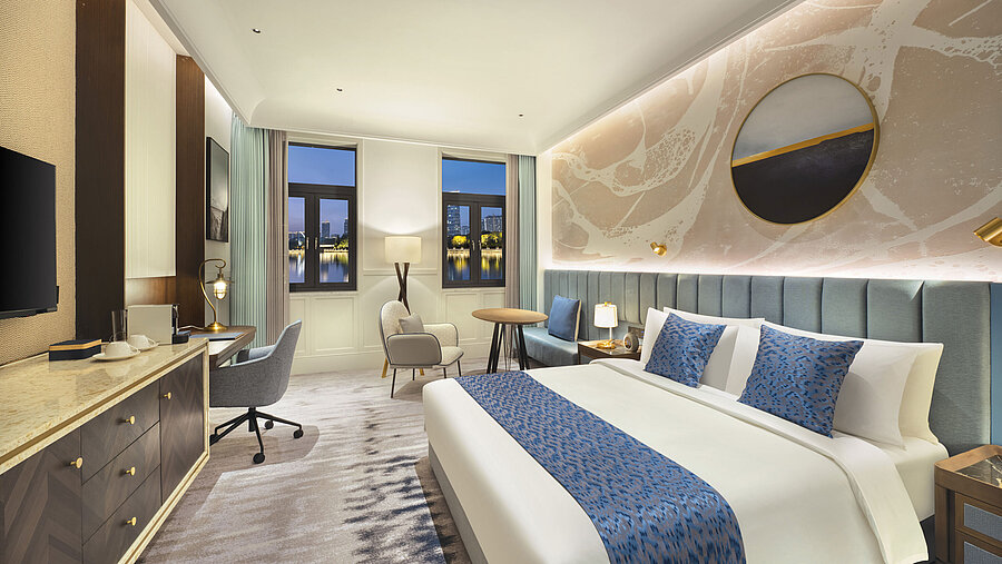 Spacious hotel room with modern design, cosy seating area and lake view at Maritim Hotel Taicang