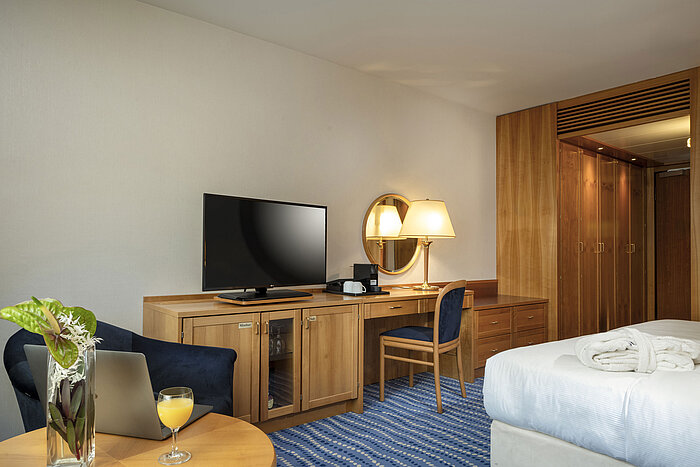 Desk with TV and lamp in a Superior room with wooden furnishings and blue accents.