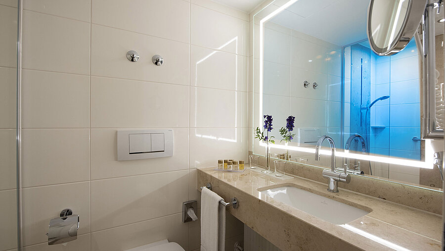 Bright bathroom with large mirror and amenities at Maritim Hotel Titisee