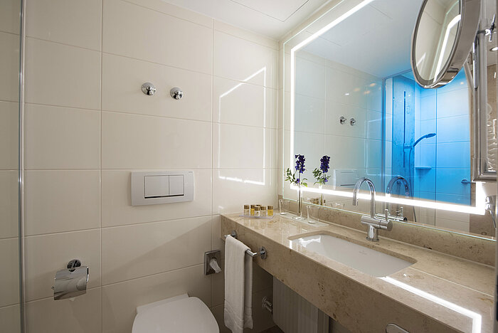 Bright bathroom with large mirror and amenities at Maritim Hotel Titisee